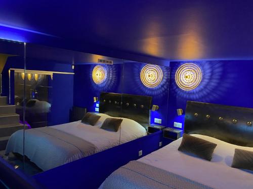 里尔Private Room & Spa avec jacuzzi privatif的一间卧室配有两张带蓝光灯的床