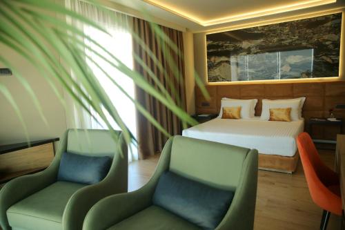 伏罗拉Kraal Hotel Vlore的酒店客房,配有一张床和两把椅子