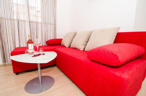 杜布罗夫尼克艾拉公寓酒店的一张带桌子的红色沙发以及一瓶葡萄酒