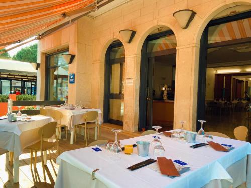 索托马里纳Hotel Ammare的餐厅设有白色的桌椅和窗户。