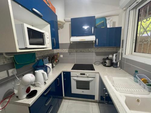 舍尔谢Mon petit cocon的厨房配有蓝色橱柜和白色炉灶烤箱。