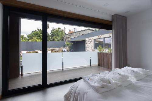 维亚纳堡Abraços dos Avós - Casas de aldeia的一间卧室设有大窗户和一张铺有白色床单的床。