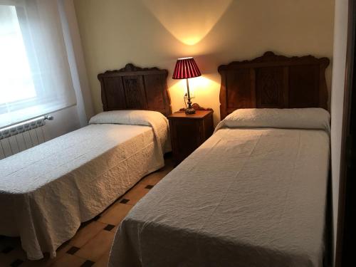 桑亨霍Playa Silgar en Galicia的一间卧室设有两张床和一张桌子上的台灯。