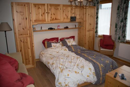 谷雪维尔Courchevel 1550 – VERITABLE SKI AUX PIEDS – APPARTEMENT LES TOVETS T2 – 47m2 – 4P的一间卧室配有一张床和一张红色椅子