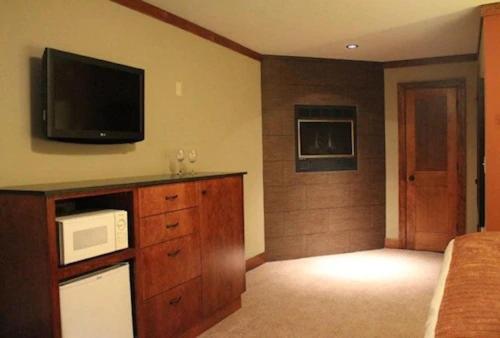 南太浩湖Avalon Lodge South Lake Tahoe的卧室配有微波炉,墙上配有电视。