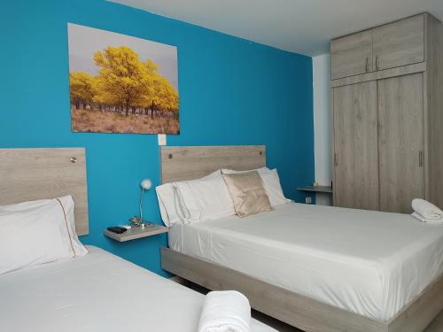 巴耶杜帕尔Escala Hotel的一间卧室设有两张床和蓝色的墙壁
