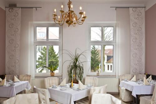 格赖夫斯瓦尔德阿德勒酒店的餐厅设有白色的桌椅和窗户。