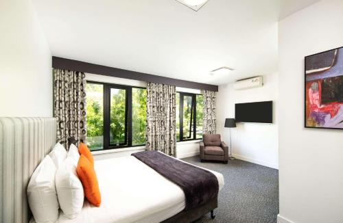 墨尔本东墨尔本舒适酒店 的一间卧室配有一张床、一把椅子和窗户。