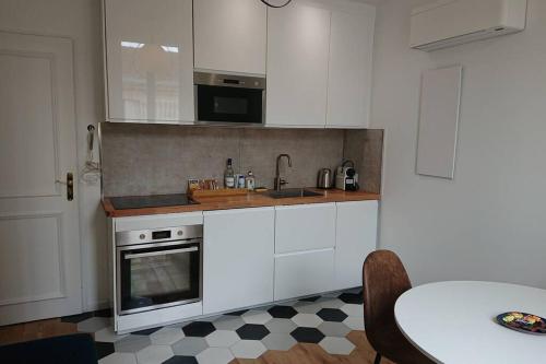 波尔多appartement 4 pers quartier Chartrons à Bordeaux的厨房配有白色橱柜、桌子和水槽。
