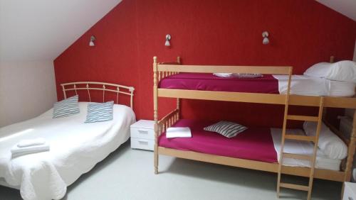 马西尼亚克Auberge des lacs的一间卧室设有两张双层床和红色的墙壁
