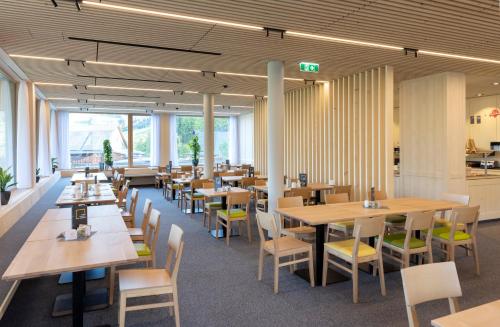 拉特恩斯JUFA Hotel Laterns - Klangholzhus的餐厅设有木桌、椅子和窗户。