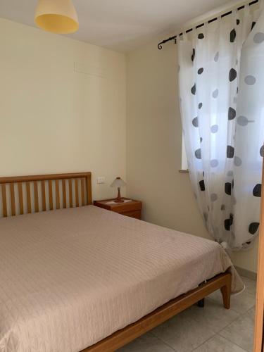 波利科罗Appartamento in Villa a Policoro的一间卧室配有床和窗帘