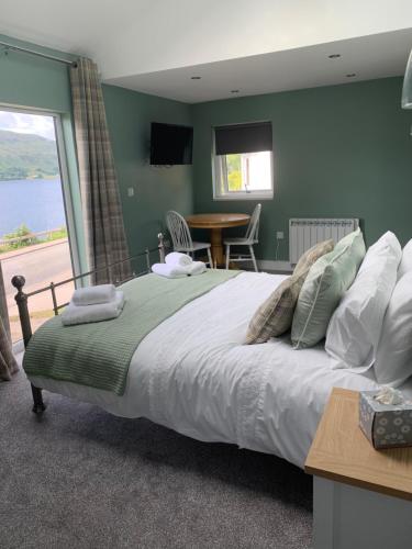 威廉堡Alt-an Retreat Lodge overlooking loch linnhe的一间卧室配有一张大床、一张桌子和一个窗户。