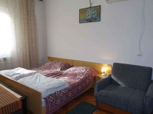 奥米沙利Apartment in Omisalj - Insel Krk 39736的一间小卧室,配有一张床和一把椅子