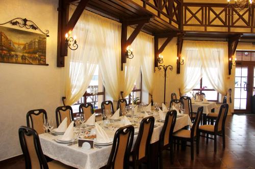 日托米尔Chalet Hotel的用餐室配有长桌、椅子和白色桌布