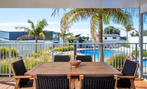 奥霍普海滩欧霍普海滩度假酒店的一个带游泳池的阳台的一张木桌和椅子