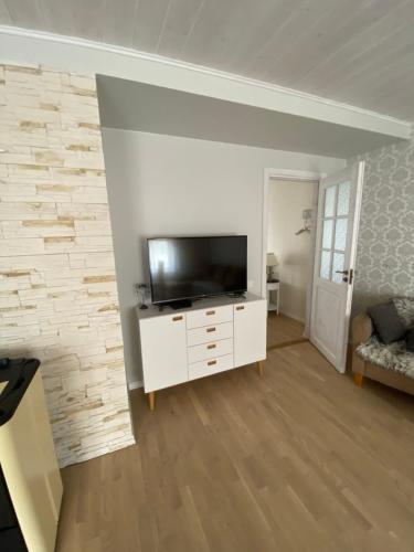 沃鲁Tamula apartament的一间客厅,客厅的白色橱柜上配有电视
