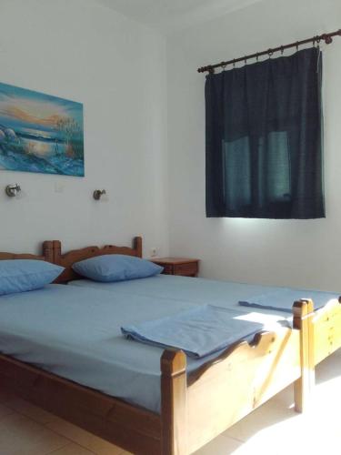 雷夫科斯卡尔帕索Nikos Taverna and Apartments的一间卧室配有一张带蓝色床单的床和一扇窗户。