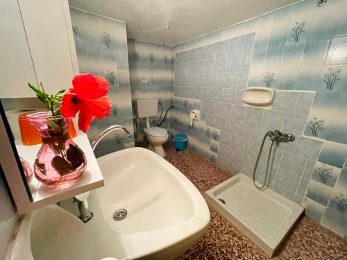 阿彻奇洛斯阿芙罗狄蒂膳食公寓的浴室设有花瓶,水槽上放着红花