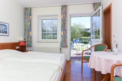贝塞尔Hotel-Pension Störtebeker的一间卧室配有两张床和一张桌子及椅子