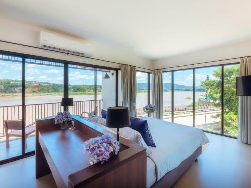 清孔Fortune Riverview Hotel Chiang Khong的一间卧室配有一张床和一张鲜花桌子