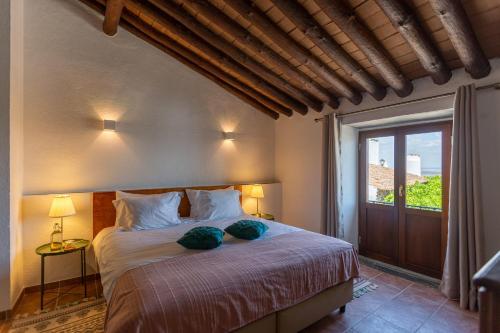蒙萨拉什Estalagem de Monsaraz的一间卧室配有一张带两个绿色枕头的床