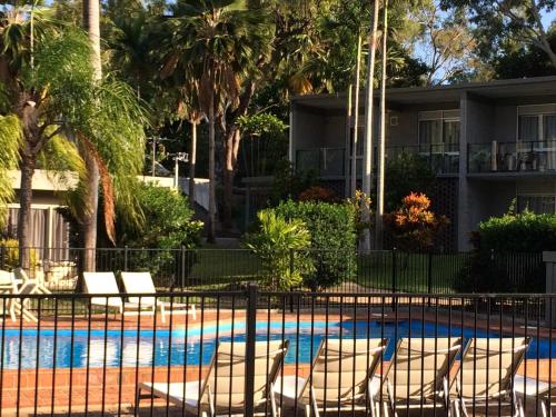 阿卡狄亚阿卡迪亚村莫泰酒店的一个带椅子和棕榈树的游泳池的度假酒店
