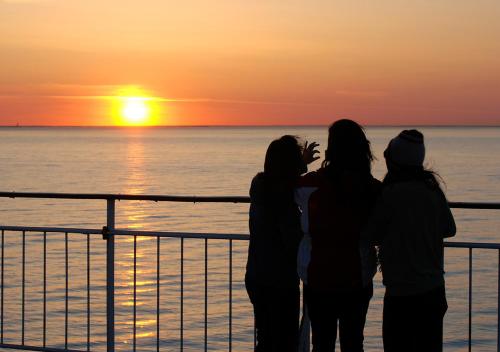 图尔库Viking Line ferry Viking Grace - One-way journey from Turku to Stockholm的三名妇女站在一艘游船上,看着日落
