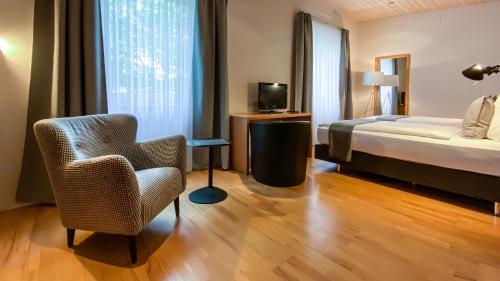 罗拉赫IMPULSIV体育度假酒店的一间卧室配有一张床、一把椅子和电视