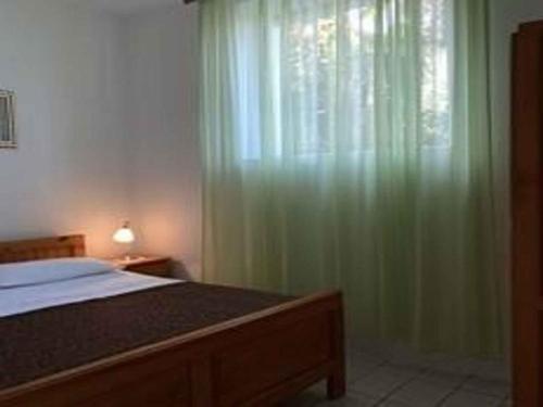 尼亚卢卡Holiday home in Vela Luka 6375的一间卧室设有床铺和一个带绿色窗帘的窗户。