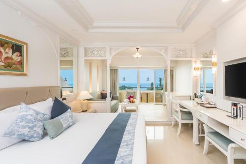 南芭堤雅Royal Cliff Beach Hotel Pattaya的一间卧室配有一张床和一张书桌及电视