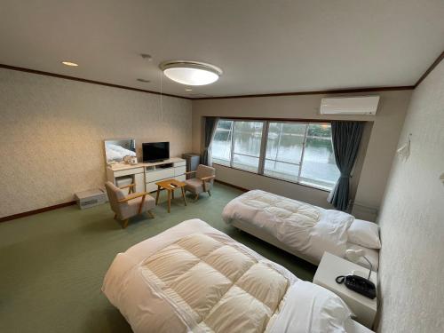 白滨Marina Hotel Kaikuu的酒店客房设有两张床、一张桌子和一台电视。