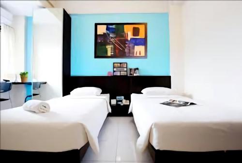 安汶LeGreen Suite Ratulangi的一间设有两张床和蓝色墙壁的客房