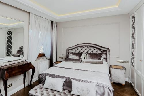 沃姆扎Apartament Royal的一间白色卧室,配有一张床和一架钢琴