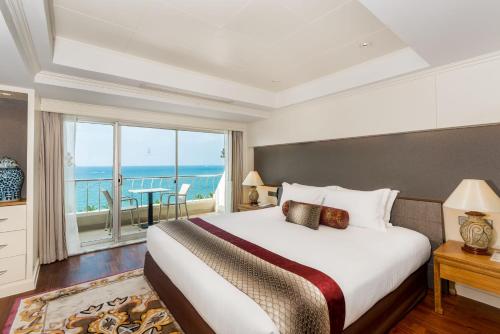 南芭堤雅Royal Wing Suites & Spa Pattaya的一间卧室设有一张大床,享有海景