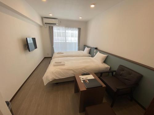 宫古岛HOTEL GranLeaf Miyakojima的酒店客房,配有两张床和椅子