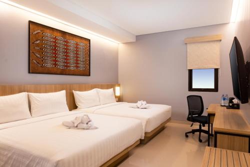 查亚普拉BATIQA Hotel Jayapura的酒店客房配有两张床和一张书桌