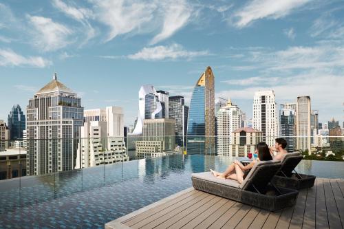曼谷曼谷新浩中央酒店 - an IHG Hotel的两个女人坐在建筑物屋顶的椅子上