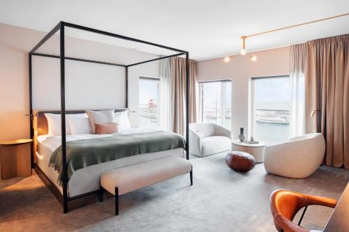 赫尔辛堡Clarion Hotel Sea U的一间卧室配有一张天蓬床和一把椅子