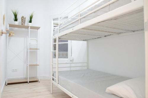 巴塞罗那Apartamento NUEVO con encanto en SAGRADA FAMILIA的卧室设有白色墙壁和白色双层床