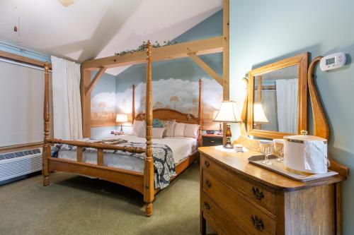 米勒斯堡The Barn Inn Bed and Breakfast的一间卧室配有一张天蓬床和木制梳妆台。
