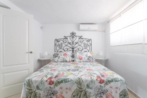 贝莱斯Casa Vistas Axarquia的白色卧室配有一张带花卉床罩的床