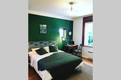 比亚里茨Villa de charme parc fleuri, arboré et piscine à BIARRITZ的一间卧室设有绿色的墙壁、一张床和一张书桌