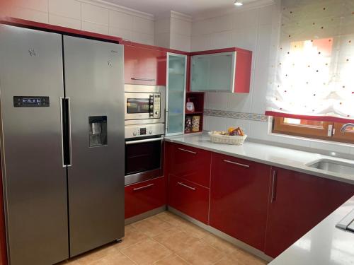 VargasChalet Individual en Vargas, Cantabria的厨房配有红色橱柜和不锈钢冰箱