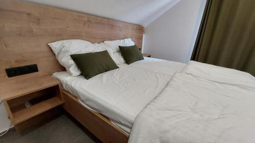 诺瓦佩奇Apartmány Jura的一张带白色床单和绿色枕头的床