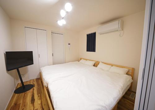 东京スポルト東京的卧室配有白色的床和平面电视。