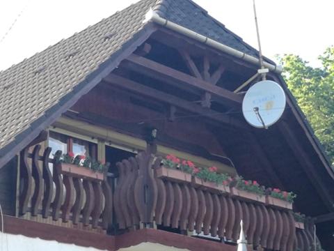 HáromhutaErdei Szalonka Vendégház的一座带鲜花和钟表的建筑阳台