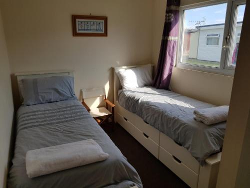 坎伯利Camber Sands Holiday Chalets - The Grey的小型客房 - 带2张床和窗户