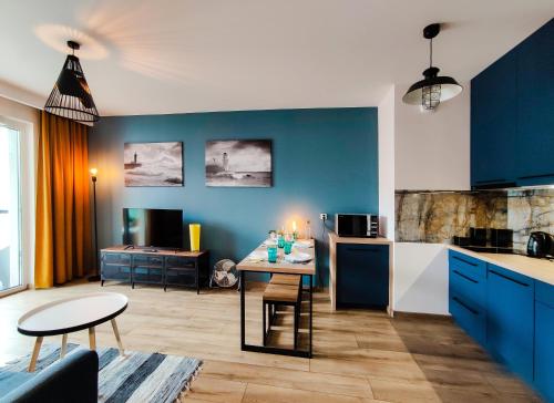 格但斯克SUNRISE HOME APARTMENTS - LIGHTHOUSE的厨房以及带蓝色橱柜和桌子的客厅。