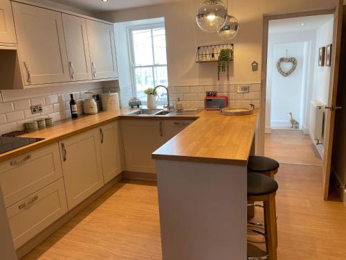 KilmingtonSt Reatham Cottage的厨房配有白色橱柜和木制台面